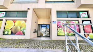 A building with a large fruit mural on the facade, a staircase leading to the entrance, and a sign indicating the address. - ALBUFEIRA SALGADOS BEACH 6 by HOMING (Albufeira)