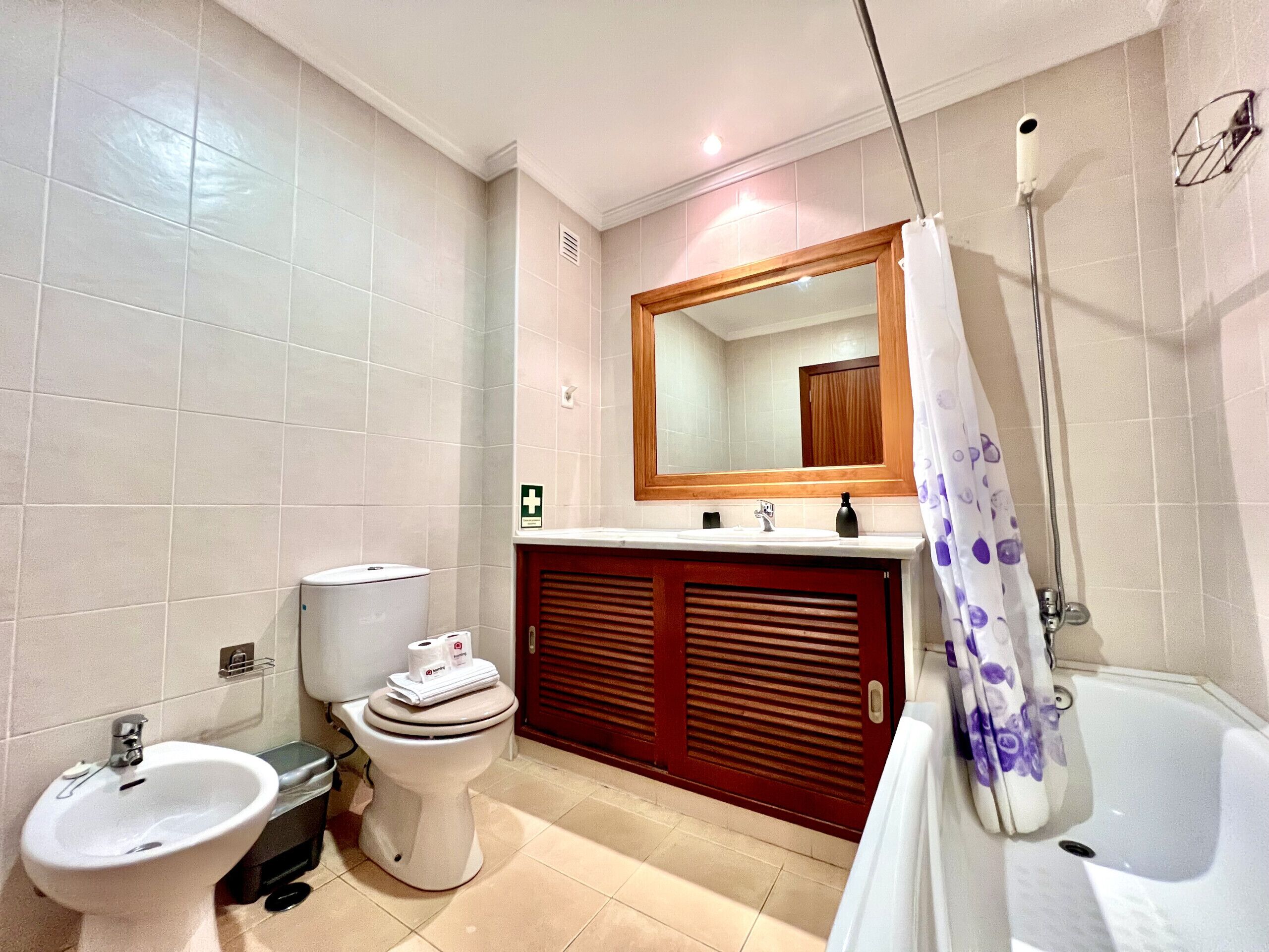 A bathroom with a toilet, bidet, sink, and bathtub.