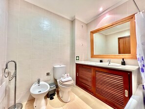 Een badkamer met een hygiëneslot, wastafel, spiegel en toilet.