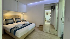 Un dormitorio con cama, mesitas de noche, un espejo y televisor.
