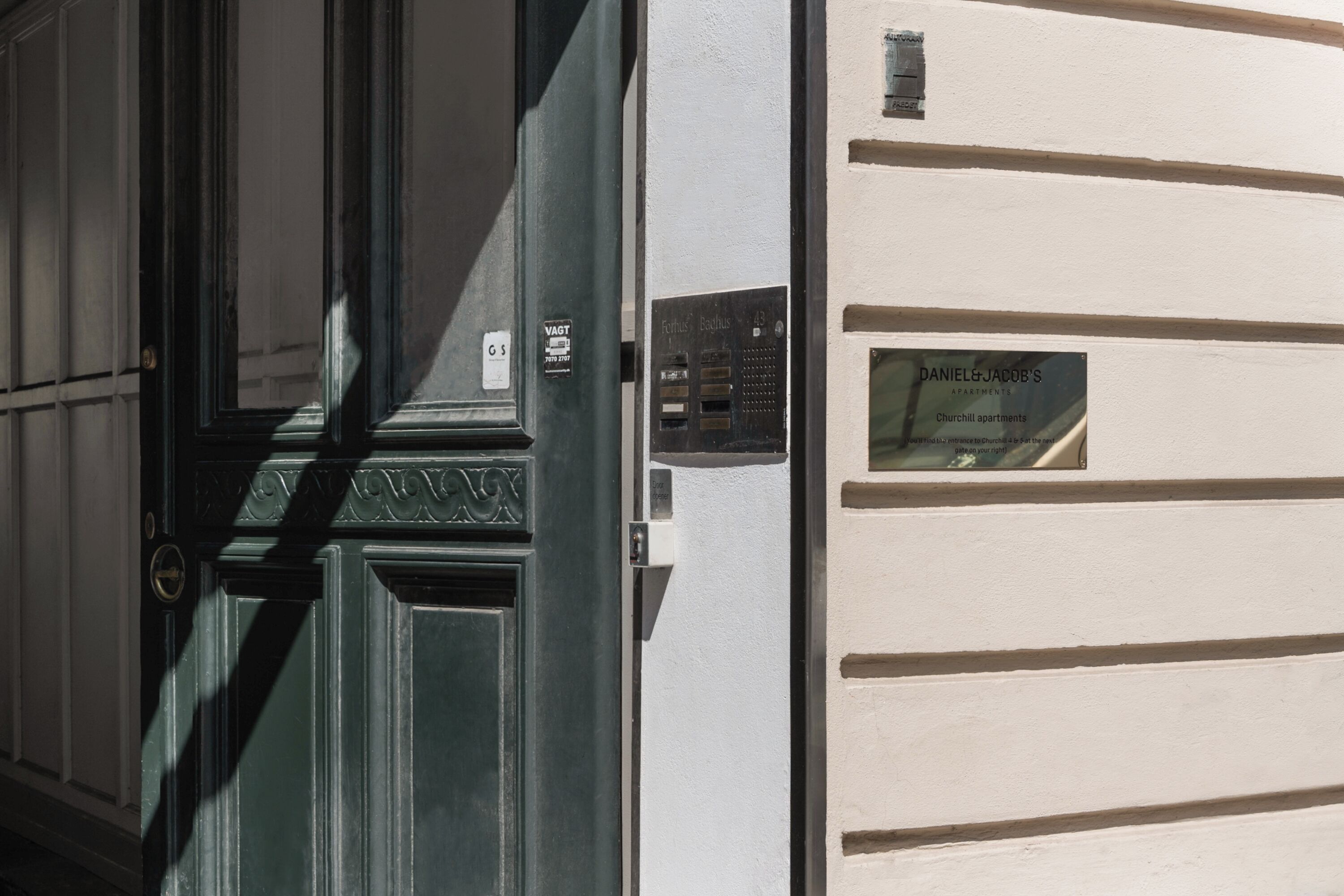 Fachada de edificio con puerta verde y una placa que indica 'Daniel & Jacob's Churchill Apartments'.