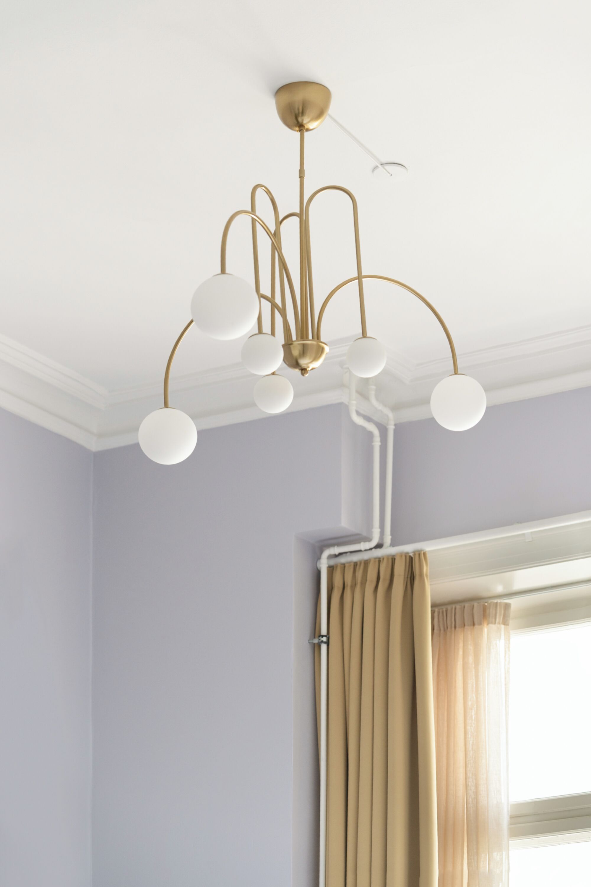 A room with a ceiling light fixture and a window with curtains.