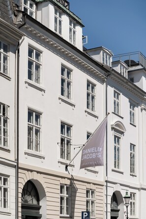 Een wit gebouw met veel ramen en een vlag waarop staat: Daniel & Jacob's Apartments.