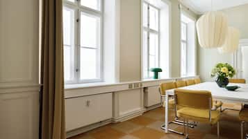Un comedor con una mesa blanca, sillas amarillas y un jarrón verde con flores.