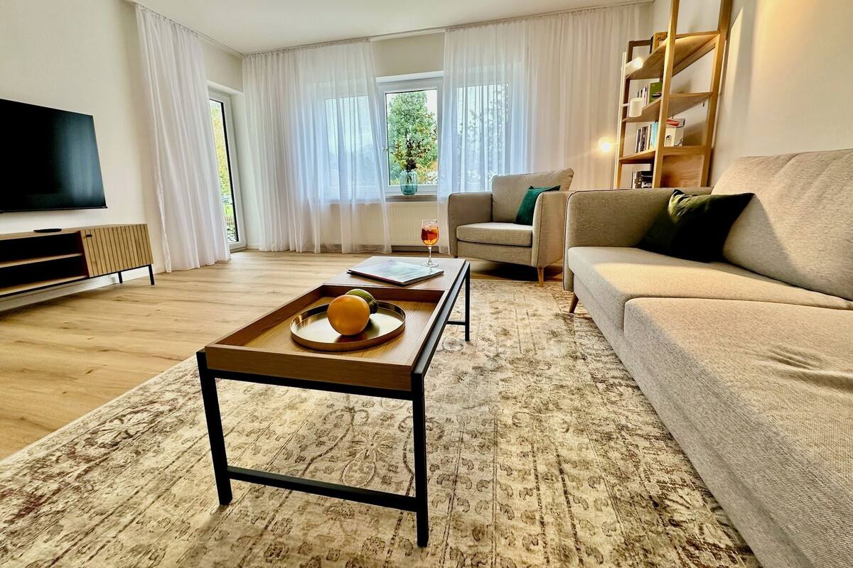 A living room with a sofa, a coffee table with fruit, a TV, and a bookshelf.