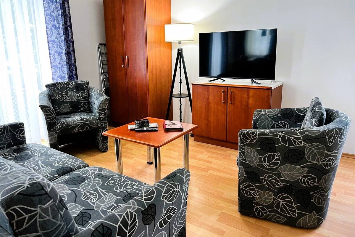 A living room with a sofa, armchair, and a TV.