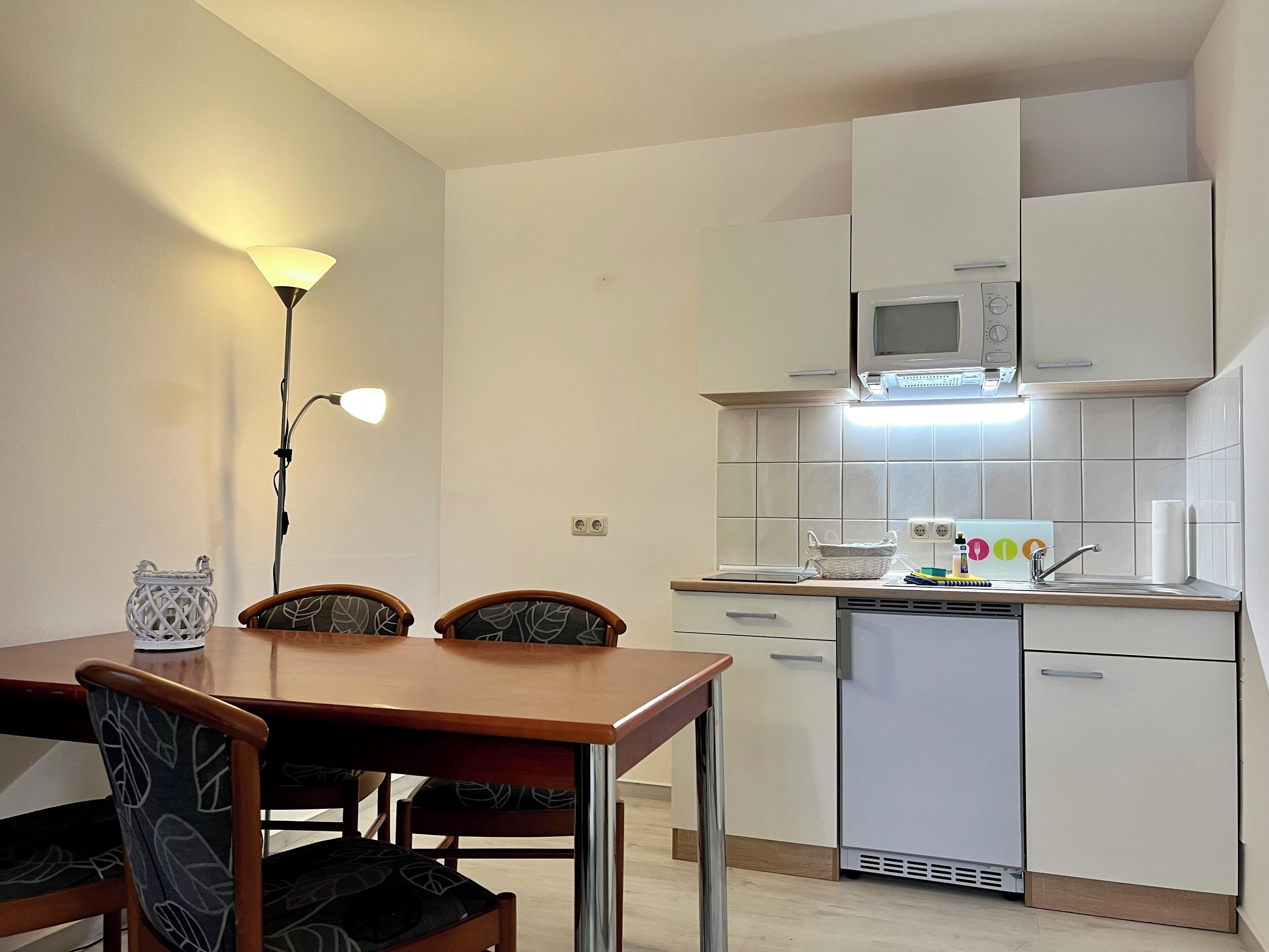 A compact kitchen with a dining area, featuring a microwave, a sink, and a dishwashing unit.
