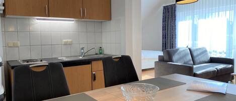 A modern kitchen with wooden cabinets, a sink, and a dining area with a table and chairs.
