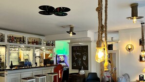 A bar area with a jukebox, shelves of bottles, and a chalkboard menu.