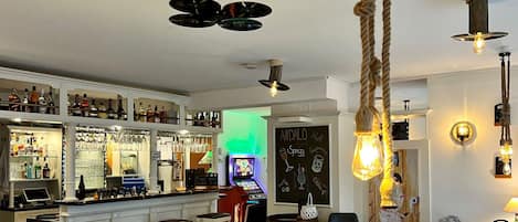 A bar area with a jukebox, shelves of bottles, and a chalkboard menu.