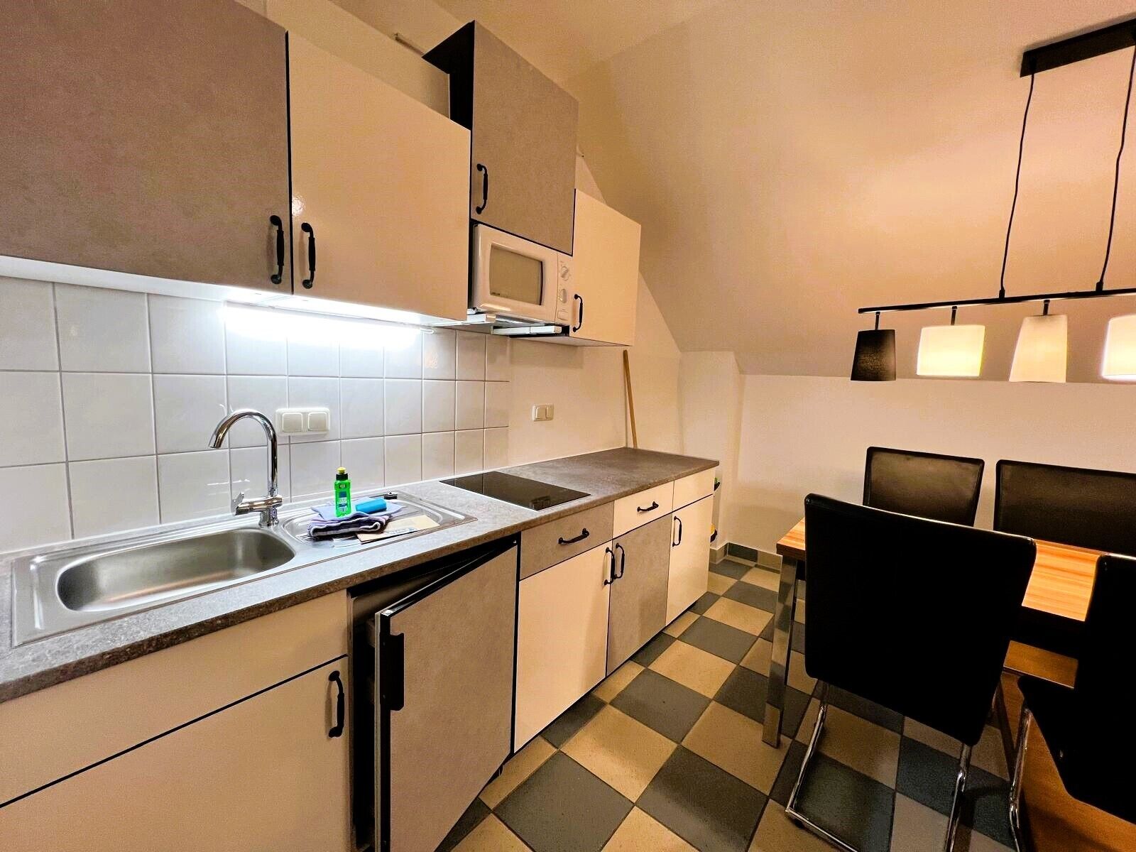 Une cuisine compacte équipée d’un évier, d’un four à micro-ondes et d’un coin repas avec une table et des chaises.