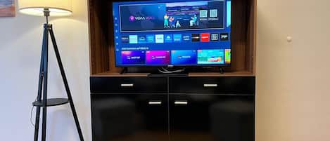 Et fladskærms-tv i et træskab med en lampe ved siden af.