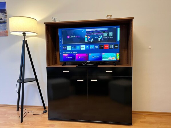 A flat-screen TV in a wooden cabinet with a lamp beside it.