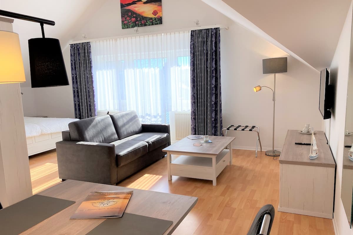 A modern living room with a sofa, a coffee table, a desk, and a bed.