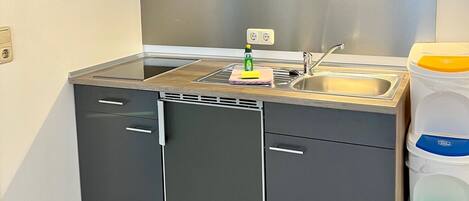 A compact kitchen with a microwave, sink, and storage cabinets.