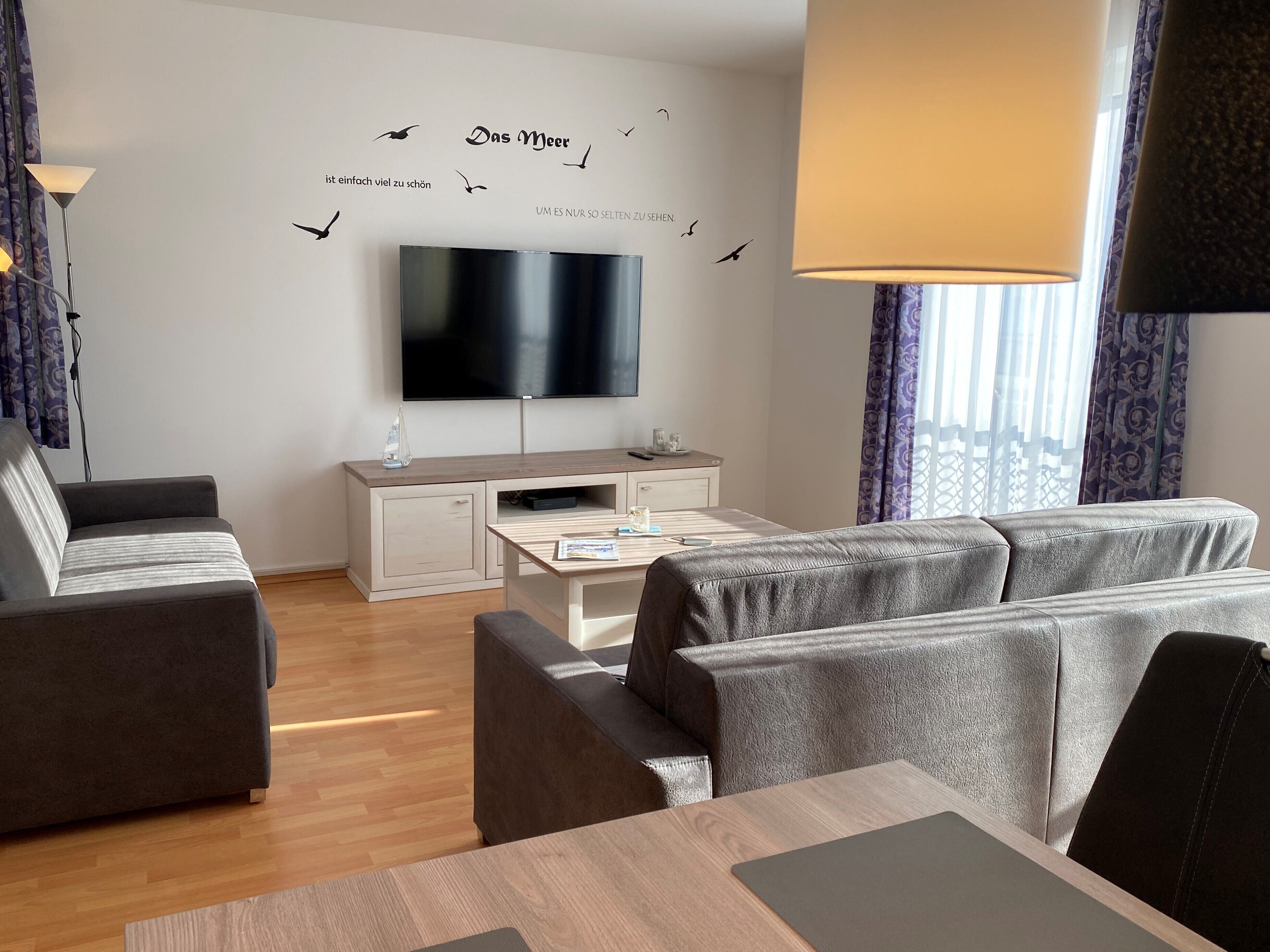 Een moderne woonkamer met een flatscreen televisie, een bank, een salontafel en een bureau.
