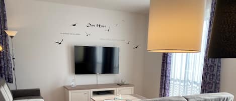 Een moderne woonkamer met een flatscreen televisie, een bank, een salontafel en een bureau.