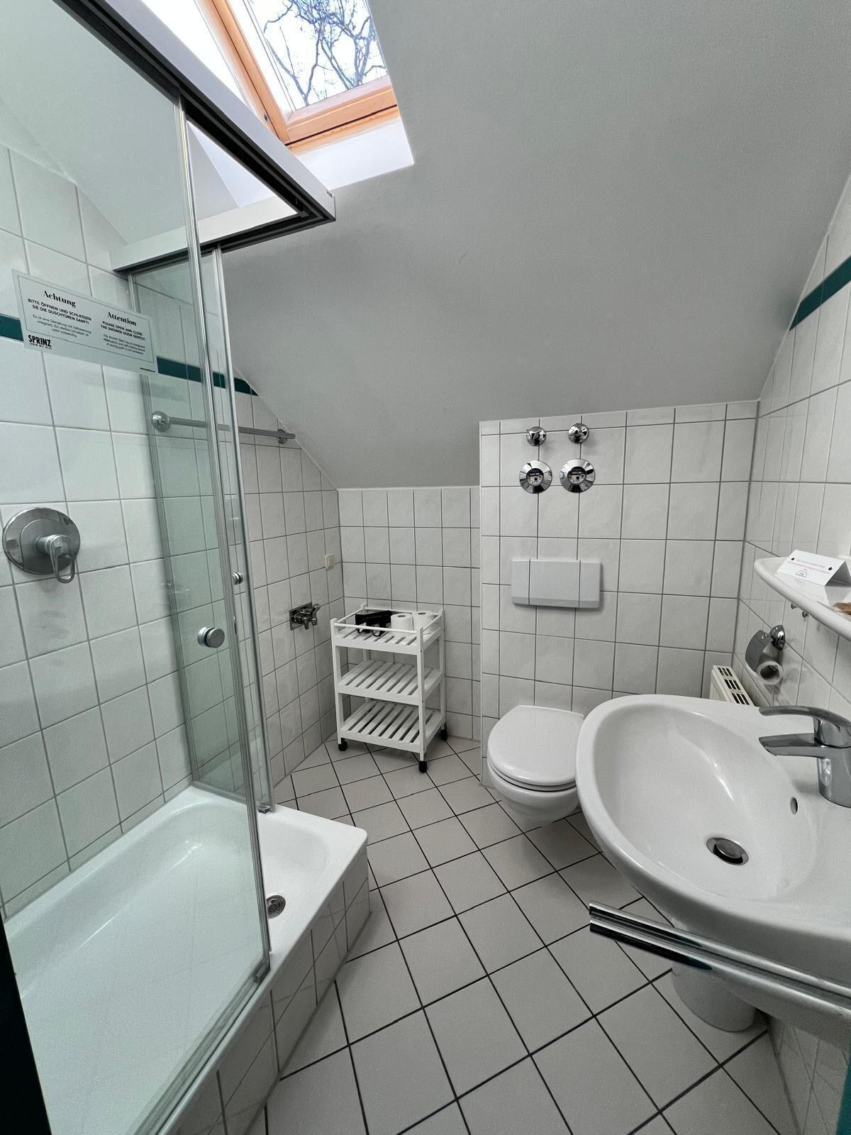 Une salle de bain moderne avec une douche à parois de verre, un lavabo blanc et des toilettes.