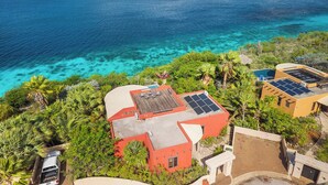 A coastal property with a pool, solar panels, and lush vegetation. - Villa La Brisa with a tropical garden, private pool and spectacular views (Kralendijk)