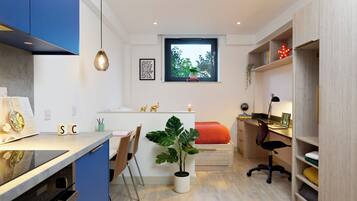 A compact, modern room with a kitchenette, a dining area, and a workspace.