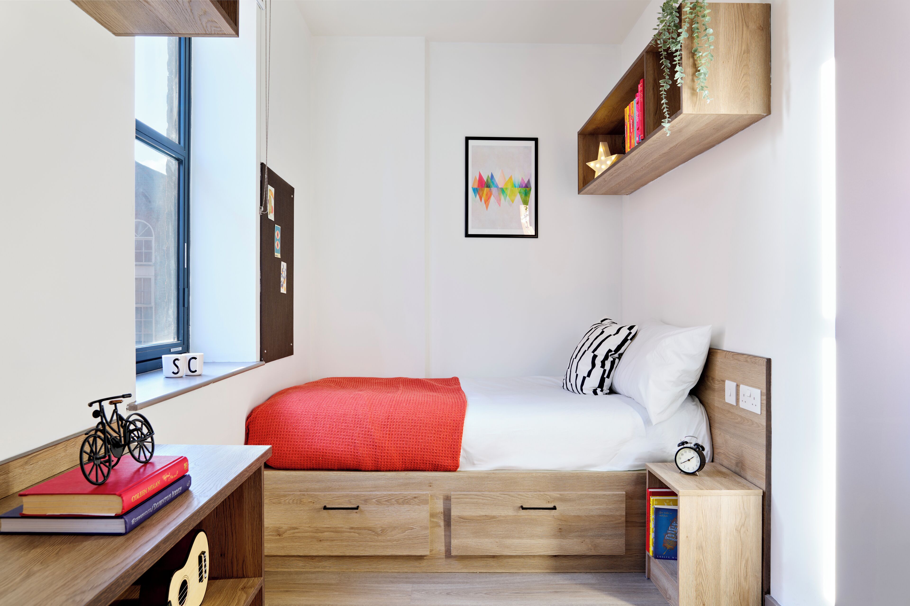 A compact bedroom with a bed, bedside table, and a window.