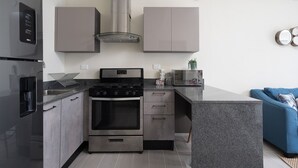 A modern kitchen with a built-in stove, oven, and stainless steel range hood. - Cozy 1BR in Panorama Lake • Pool & Beach (PUNTA CANA)