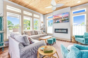 A spacious living room with a sectional sofa, a coffee table, and teal armchairs.