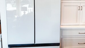 A kitchen with white cabinets, a white refrigerator, and a wooden countertop.