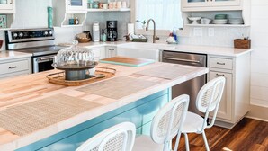A modern kitchen with a central island, white cabinetry, and a chandelier.