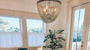 A dining area with a wooden table, teal chairs, a chandelier, and a potted plant.
