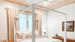 A four-poster canopy bed with a wooden ceiling and a ceiling fan.