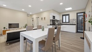 Een moderne keuken met witte kastjes, een magnetron en een betegelde spatwand.