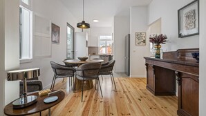 Una cocina moderna con suelo de madera, zona de comedor con sillas, una isla central e iluminación colgante.