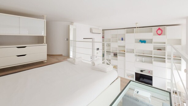 A modern bedroom with a bed, built-in wardrobe, and a glass-enclosed staircase. - GuestHost - Milan Cosy Studio on 2 levels! (Milano)
