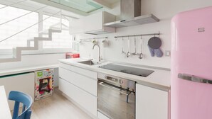 A modern kitchen with a pink refrigerator, a dishwasher, a stove, and a sink. - GuestHost - Milan Cosy Studio on 2 levels! (Milano)