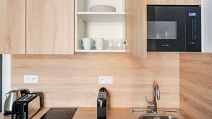 Une cuisine moderne avec des meubles en bois, un four à micro-ondes encastré, un grille-pain et une bouilloire.