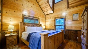 Ein Schlafzimmer einer Holzhütte mit einem Bett, Nachttischen und einem Fenster.
