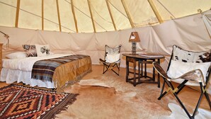 Una habitación con carpa que incluye una cama, una silla, una mesa y una alfombra.