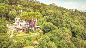 Une propriété située sur une colline, avec une grande maison dotée d’un balcon et d’un jardin.