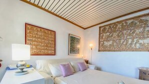Une chambre à coucher avec un lit, une table de chevet avec une lampe et un plateau contenant des théières et des tasses.