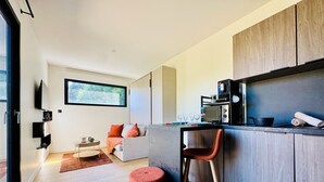 A modern kitchen with a wooden countertop, a built-in microwave, and a coffee machine. There is a seating area with a sofa and a small table. - Domaine du Mafay - Provençal Lodge (Bourg-des-Comptes)