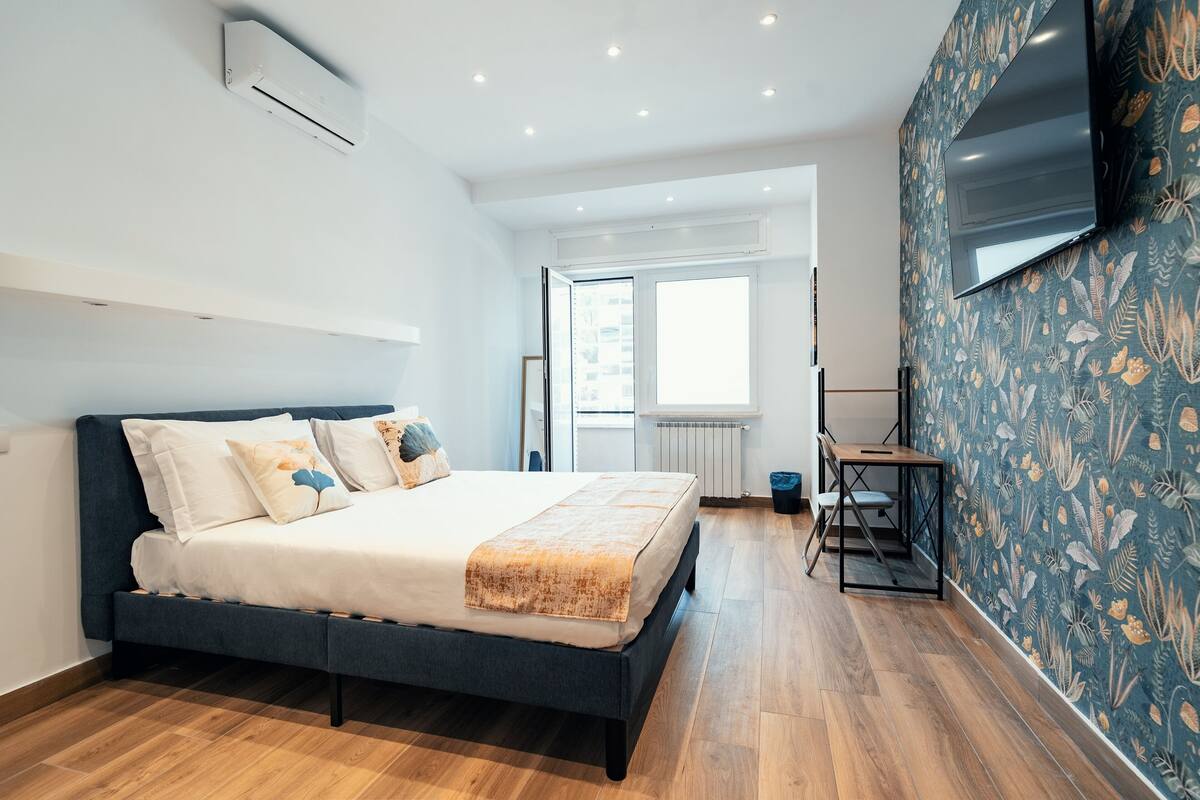 Un dormitorio moderno con cama, escritorio y televisor.