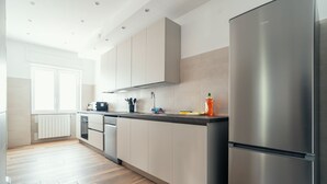 A modern kitchen with stainless steel appliances, light-colored cabinets, and a wooden floor. - Casa Mia SanPietro (Rome)