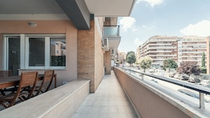 A balcony with a dining table and chairs, a view of a street with cars and buildings, and a clear sky. - Casa Mia SanPietro (Rome)