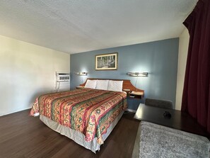 A hotel room with a bed, bedside tables, a desk, a chair, and a painting on the wall. - Motel Jesup Near US 301 (Jesup)