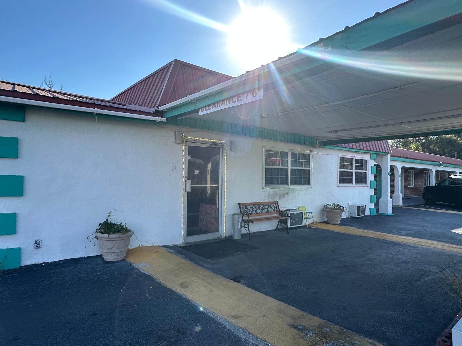 A building with a covered parking area, a bench, and a potted plant.