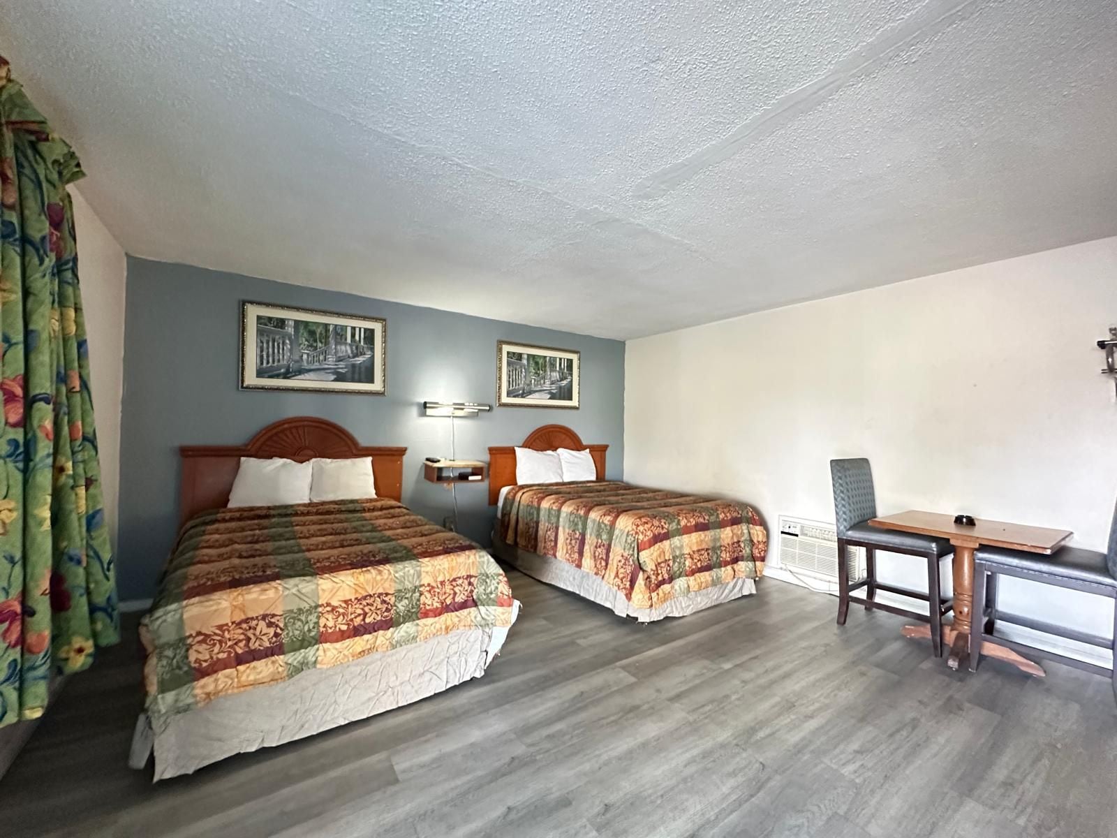 A hotel room with two beds, a desk, and a chair.