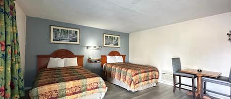 A hotel room with two beds, a desk, and a chair.