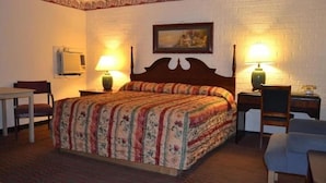 A hotel room with a wooden bed, two bedside lamps, a desk, and a chair. - Motel Jesup (Jesup)
