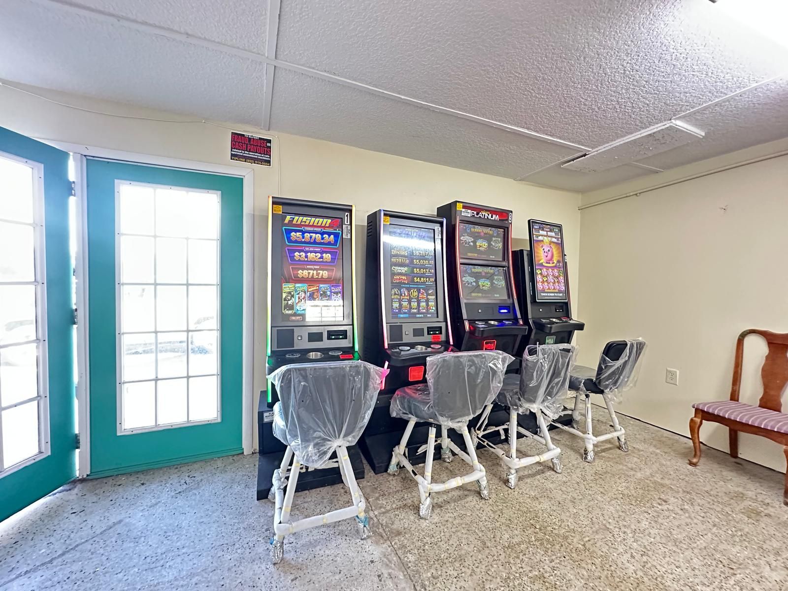 Eine Reihe von Spielautomaten in einem Raum mit einer türkisblauen Tür und einer weißen Decke.